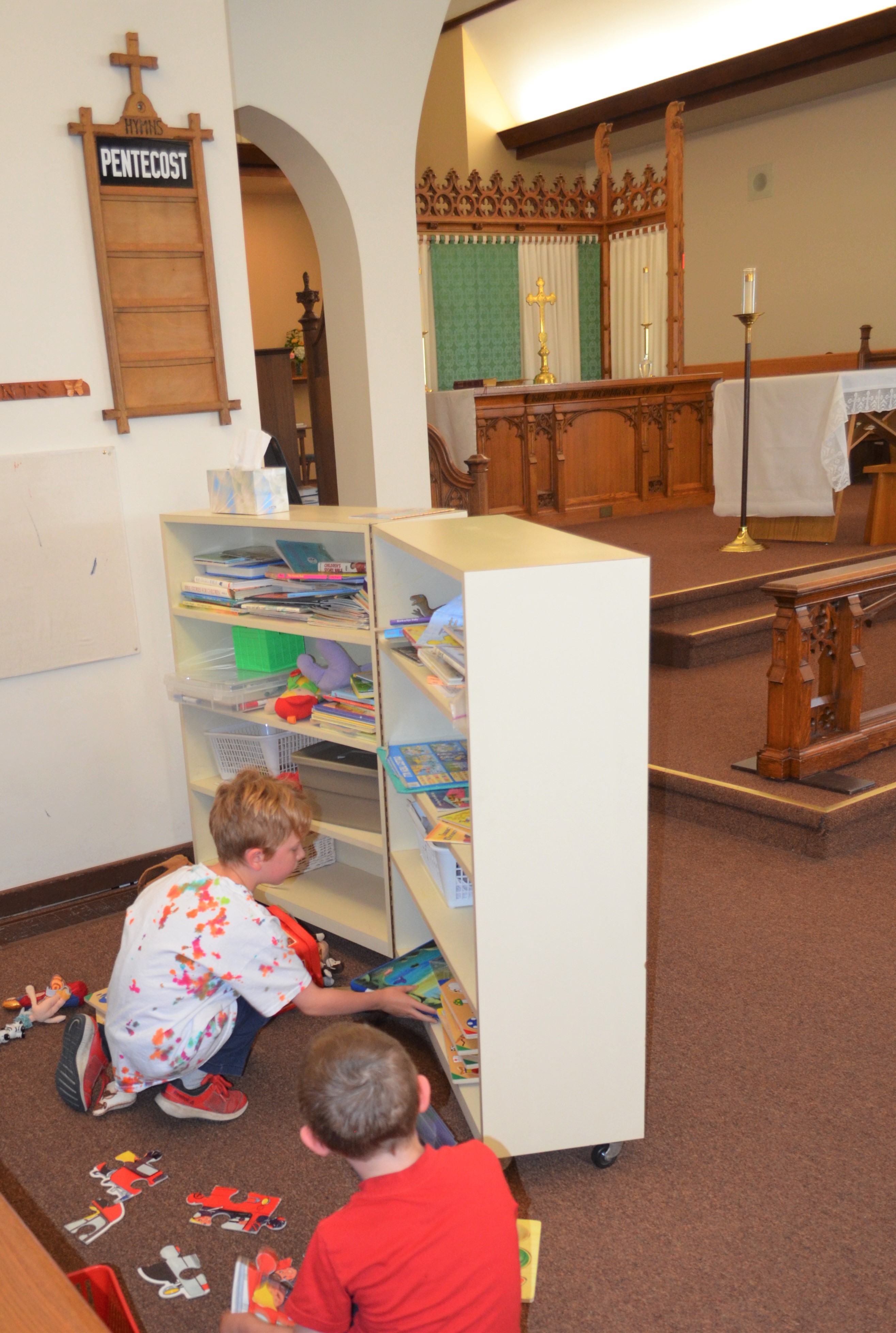 Two children playing with toys and books in the children's play area at the front of the church.