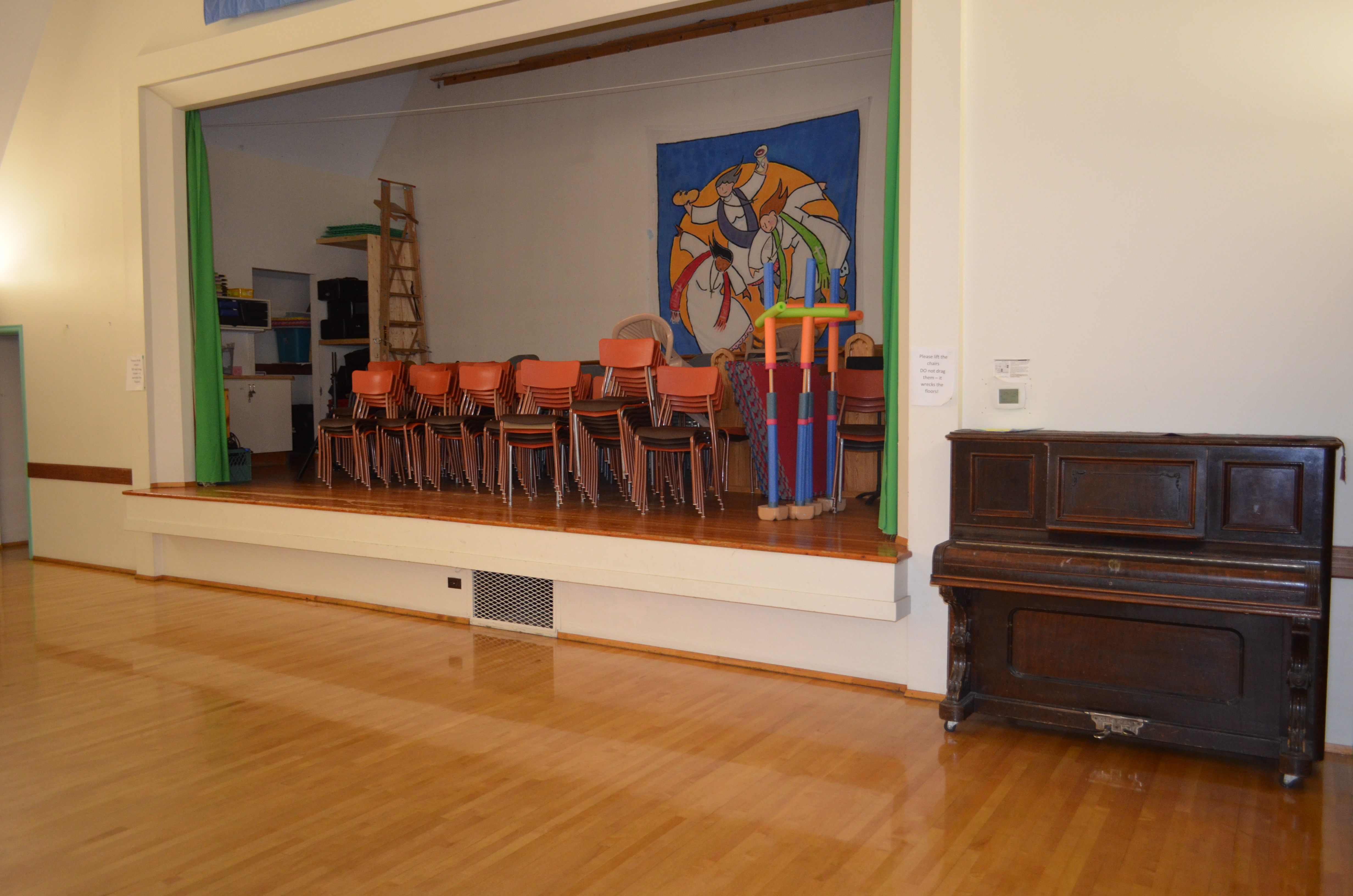 Wooden stage with curtains. Older piano next to stage.