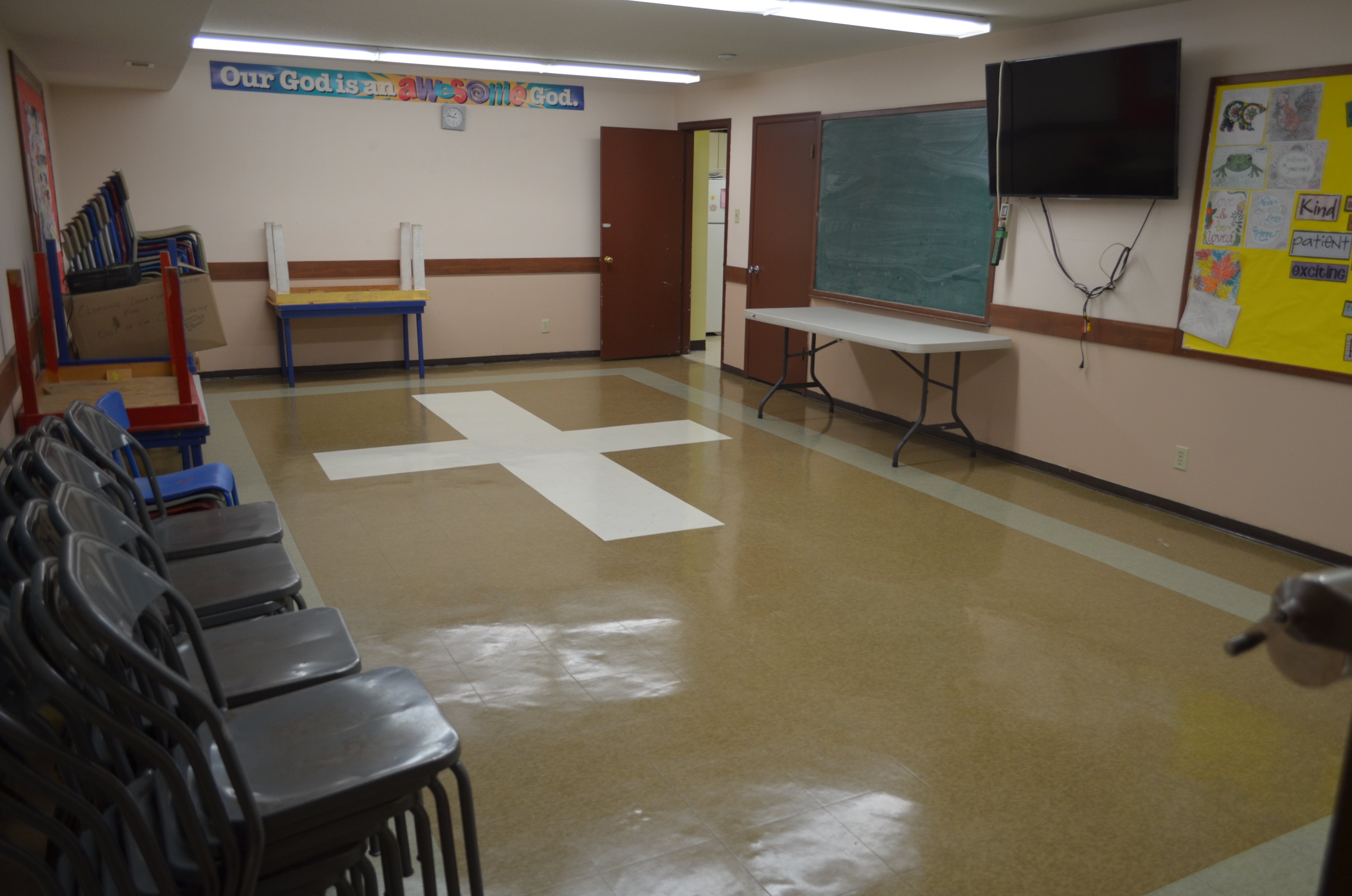Image shows Ruth meeting room which has linoleum flooring, a chalkboard and a wall mounted big screen TV. The room also has children's and adult tables.