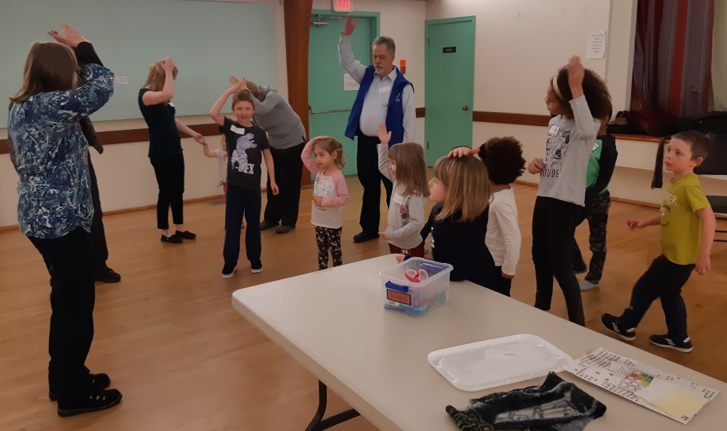 Children and adults playing the peddler says (they have their hands on their heads)